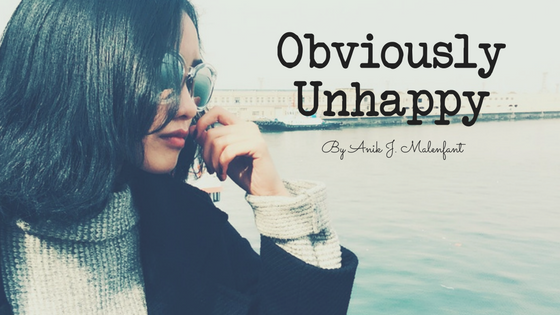 Obliviously Unhappy - Title text and credit to Anik J. Malenfant with an image of a woman looking out across the water looking unaware