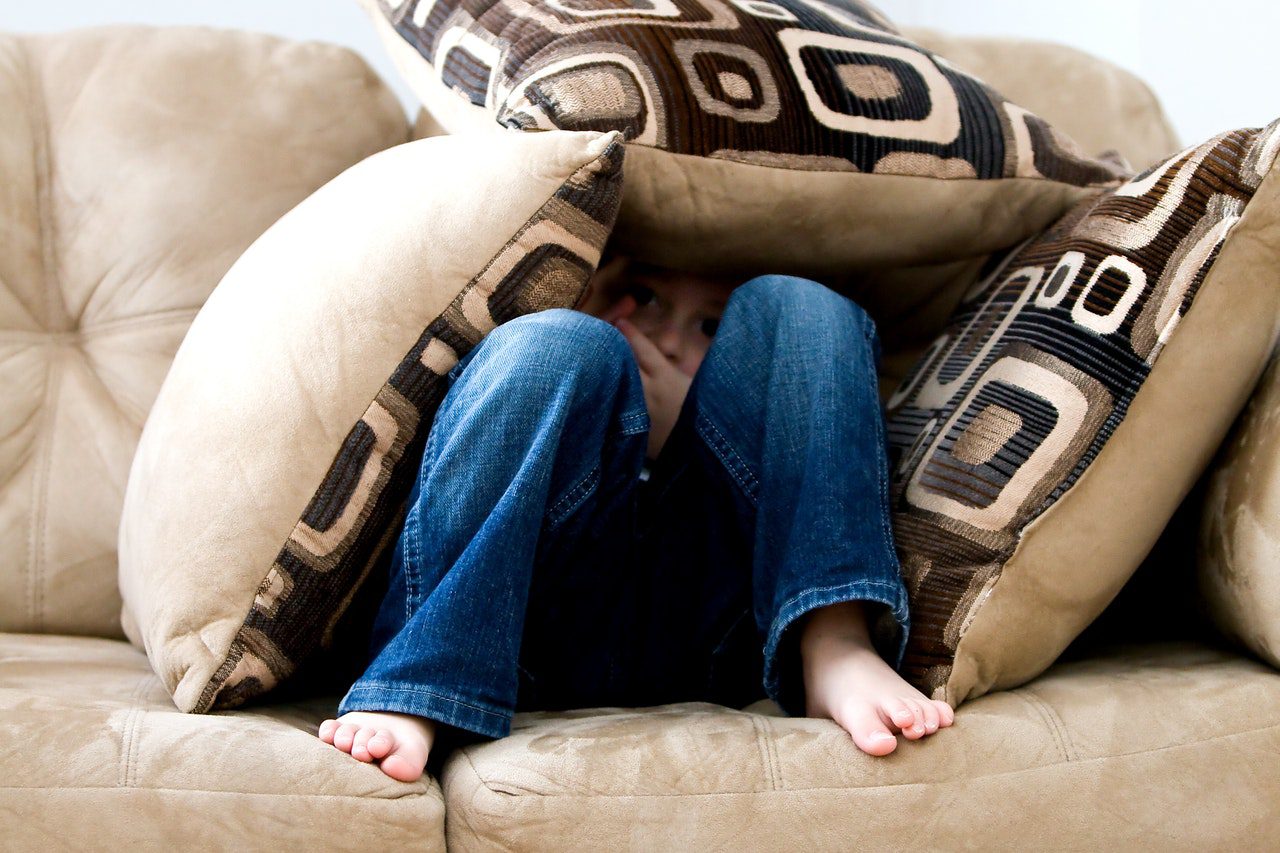 Don't let fear define your year - girl in jeans hiding in a cushion fort